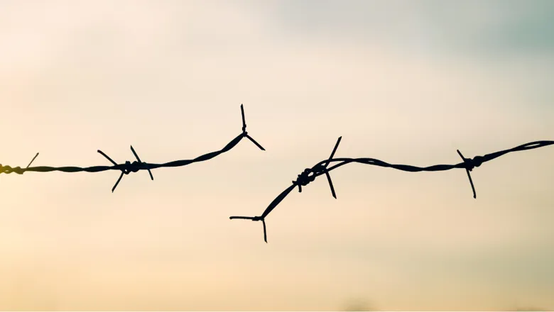 Broken barbed wire against the sky